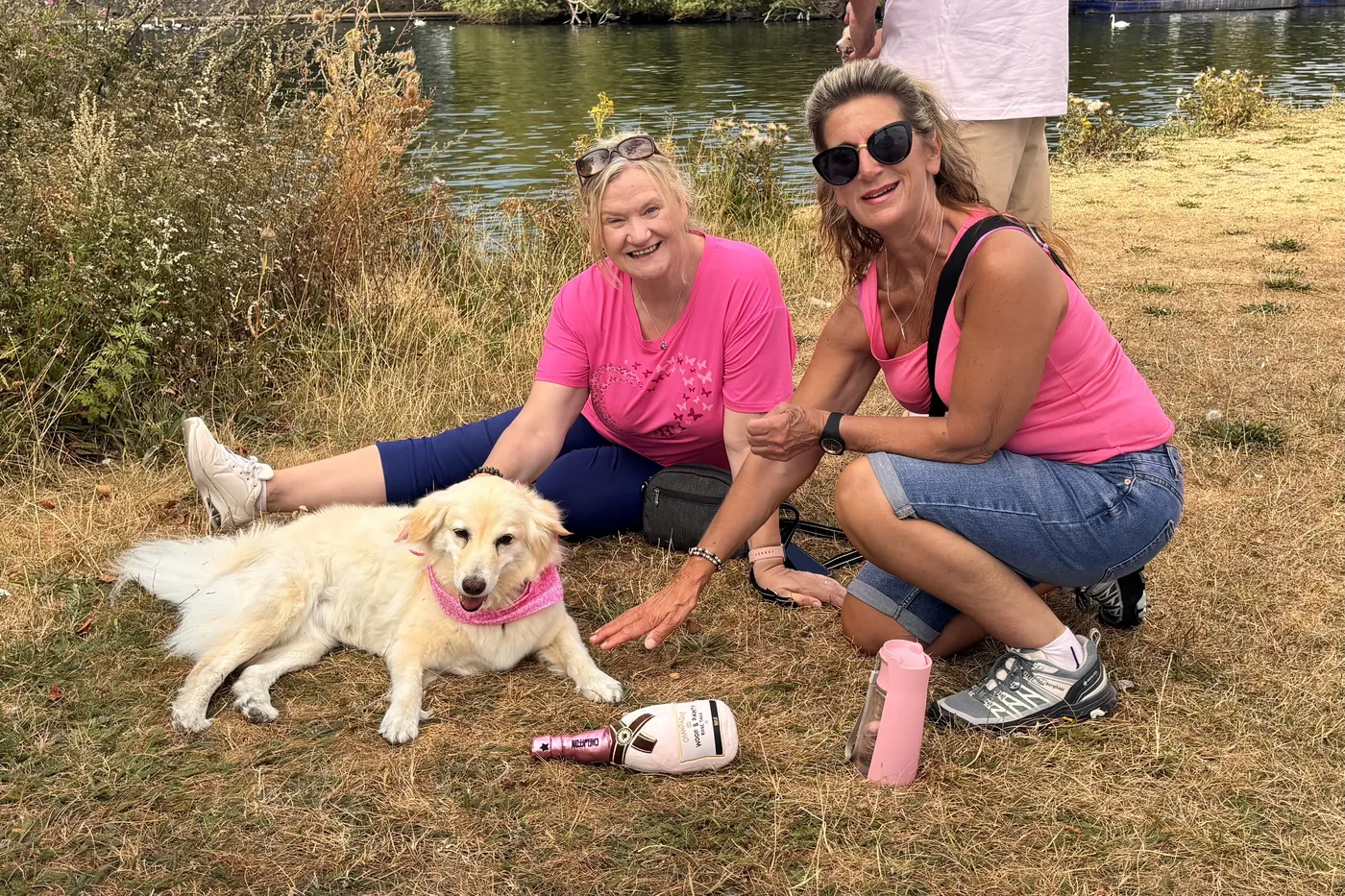 Two crew members sitting on the grass with Matilda by the river