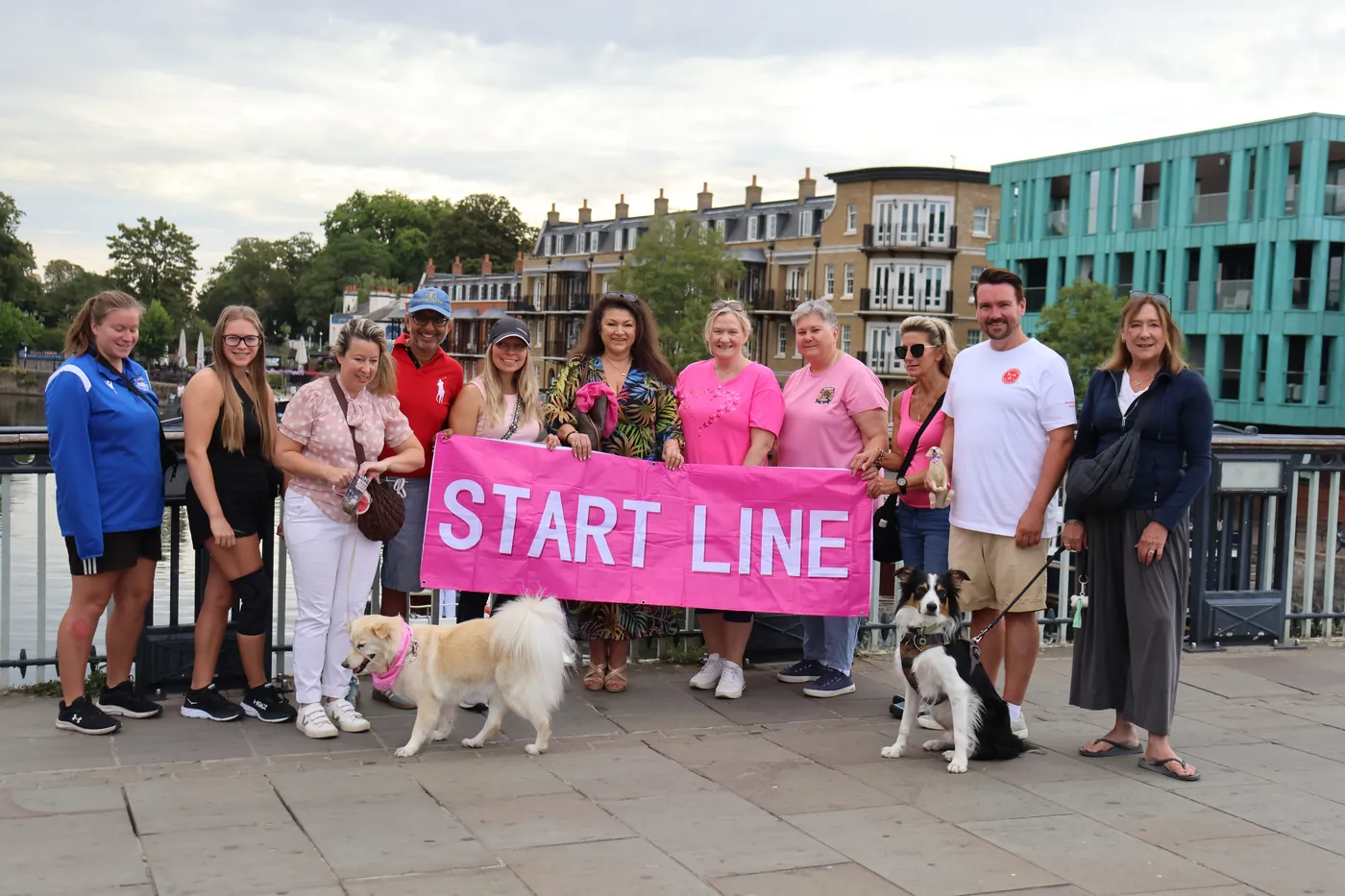 The crew at the start line with a pink banner beside the Thames